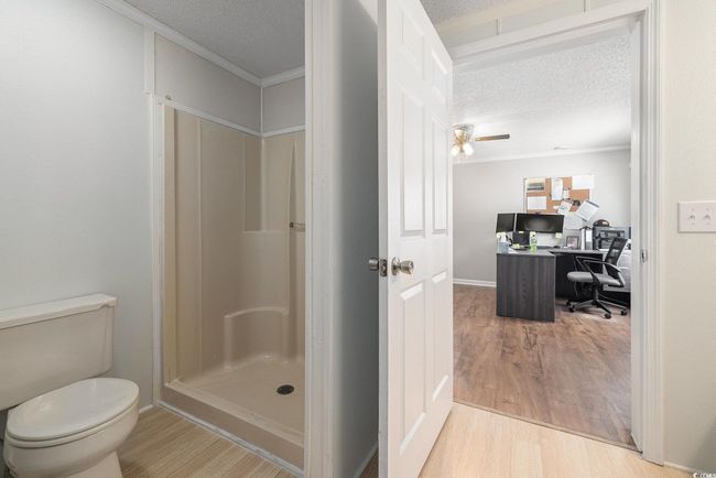 Full bath featuring a textured ceiling, wood finished floors, ornamental molding, and a stall shower | Image 19