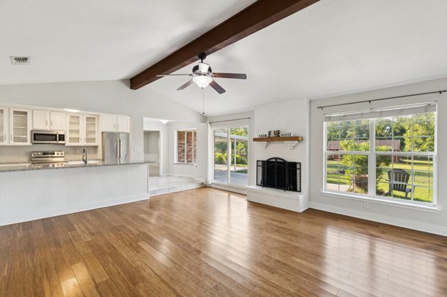 Unfurnished living room featuring light wood-type flooring, a brick fireplace, and a ceiling fan | Image 9