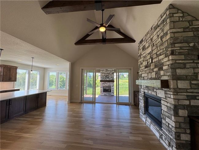 Unfurnished living room featuring a fireplace, beamed ceiling, high vaulted ceiling, wood finished floors, and a ceiling fan | Image 5