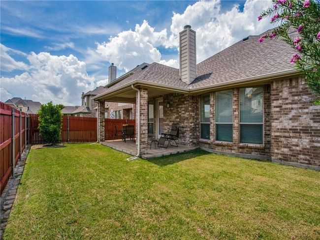 Rear view of house with a chimney, brick siding, a patio, and a shingled roof | Image 21