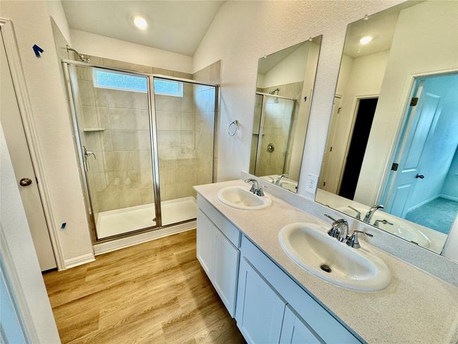 Bathroom featuring a shower stall, light wood-style flooring, double vanity, vaulted ceiling, and recessed lighting | Image 4