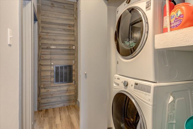 Laundry area featuring stacked washer / dryer and wood finished floors | Image 8