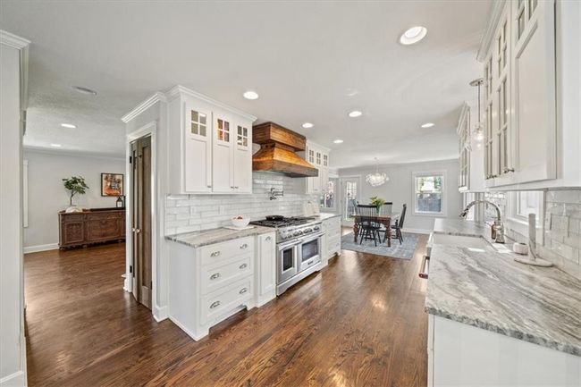 Kitchen featuring double oven range, white cabinetry, recessed lighting, and custom range hood | Image 11
