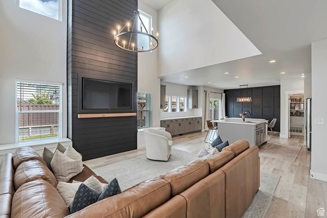 Living room featuring a chandelier, a high ceiling, plenty of natural light, light wood-style flooring, and recessed lighting | Image 4