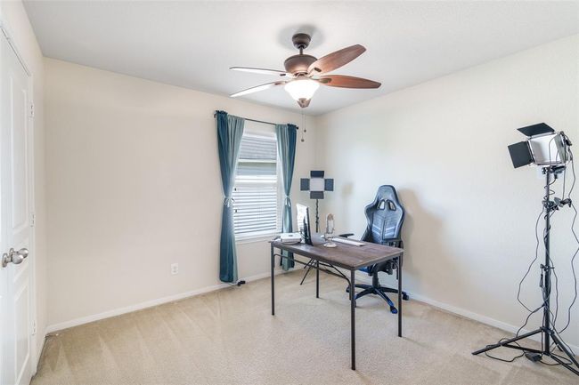 This cozy bedroom features soft carpet flooring, a ceiling fan for added comfort, and a window with privacy blinds to let in natural light while maintaining your personal space. | Image 12