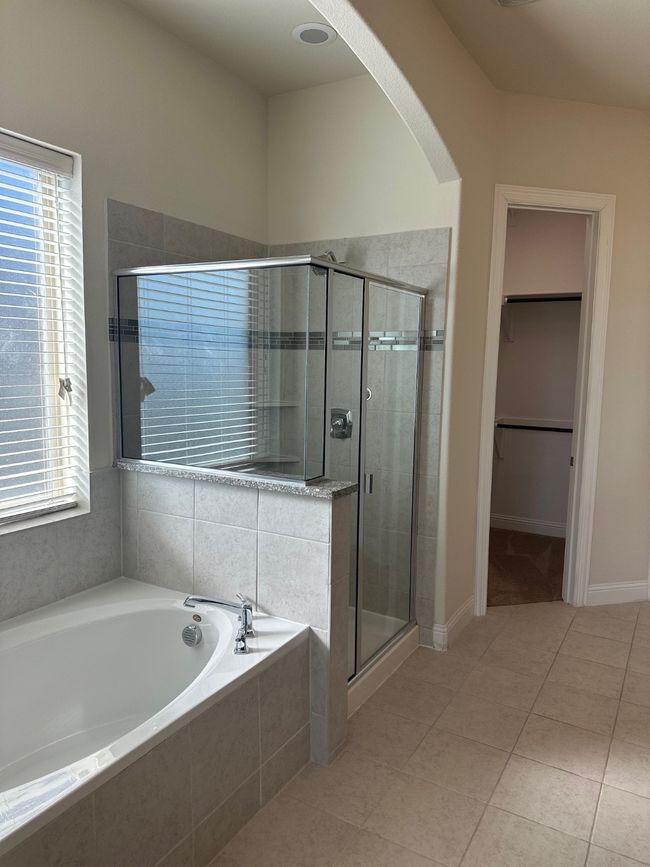 Bathroom with a garden tub, a stall shower, a walk in closet, and a healthy amount of sunlight | Image 16