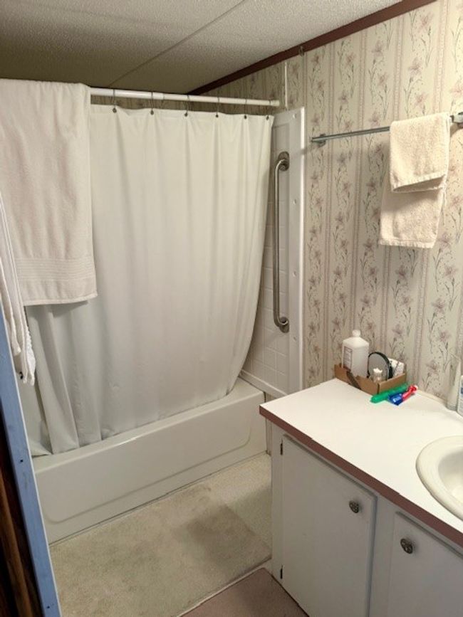 Bathroom featuring wallpapered walls, shower / bath combo, a textured ceiling, and vanity | Image 25