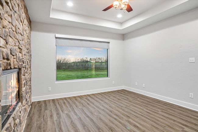 Unfurnished living room featuring a tray ceiling, ceiling fan, a fireplace, and hardwood / wood-style floors | Image 14