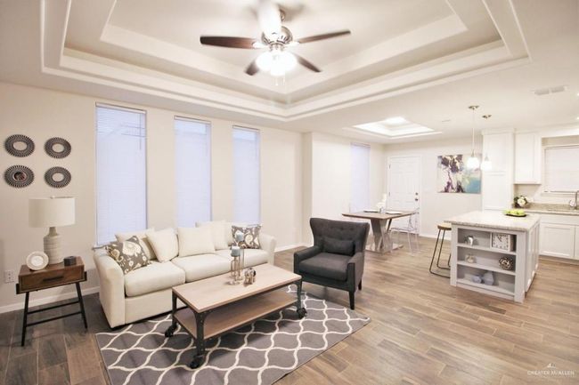 Living room featuring a tray ceiling, ceiling fan, and light wood-style flooring | Image 7