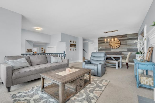 Living area with an accent wall, baseboards, stairway, wood walls, and light carpet | Image 5