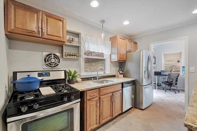 Kitchen featuring a sink, crown molding, appliances with stainless steel finishes, and light stone counters | Image 6