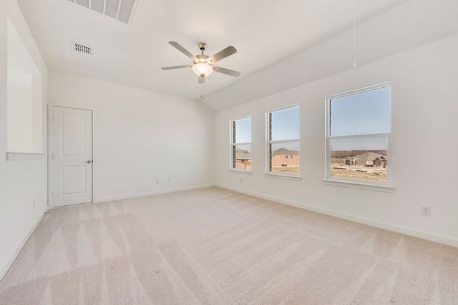 Empty room with light colored carpet, a ceiling fan, and vaulted ceiling | Image 4
