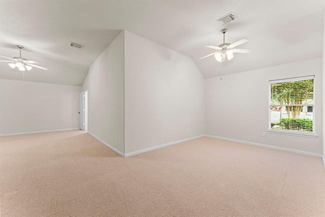 Tucked just off the primary suite, this expansive bonus room offers endless flexibility - perfect as a private sitting area, fitness space, or second office. Dual ceiling fans and a large front-facing window enhance comfort and natural light. | Image 23
