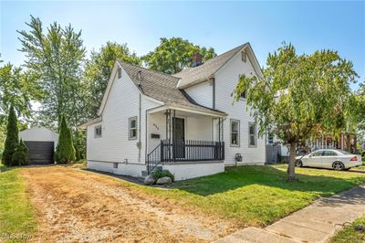 View of front of house featuring a garage, an outdoor structure, a front lawn, and covered porch | Image 1