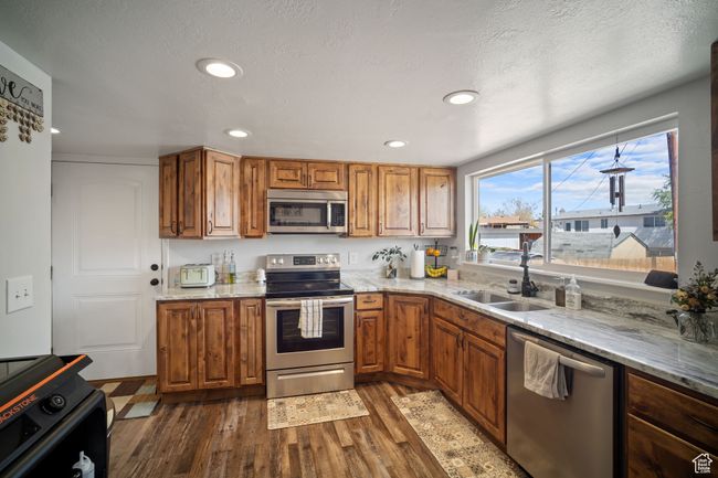Kitchen featuring appliances with stainless steel finishes, dark wood-type flooring, and brown cabinets | Image 5