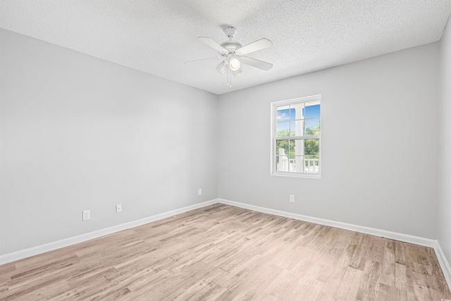Empty room featuring light wood finished floors, a ceiling fan, and a textured ceiling | Image 17