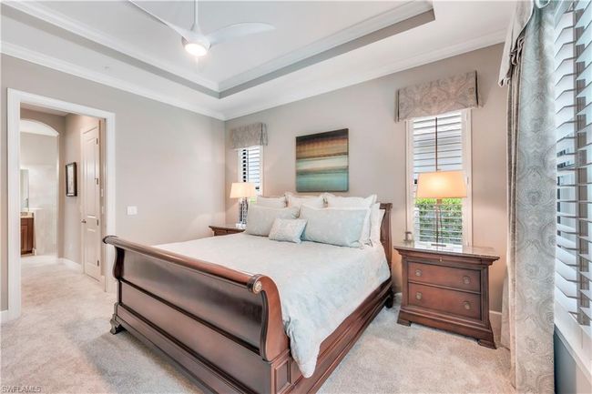 Bedroom with light colored carpet, ornamental molding, a raised ceiling, and baseboards | Image 21