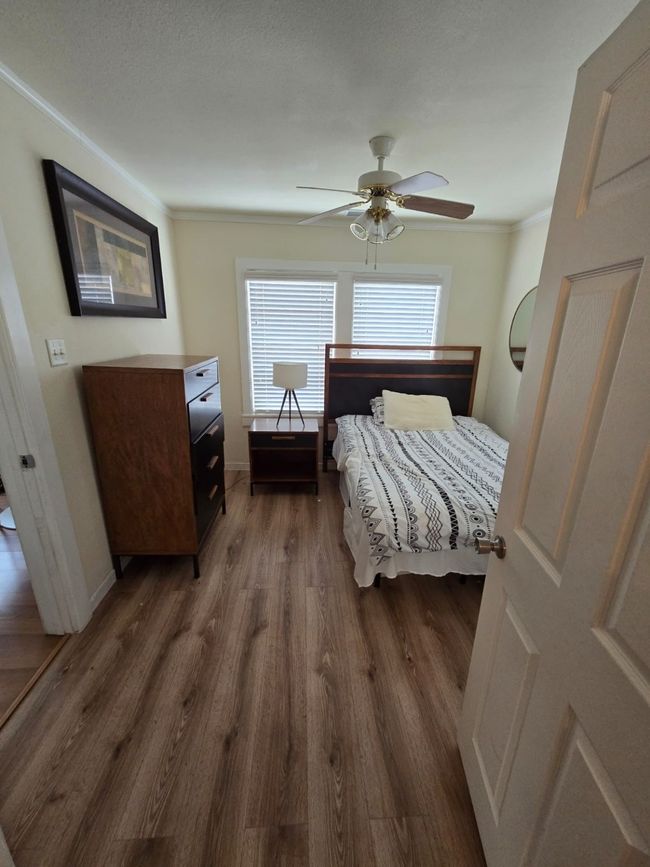 Bedroom with dark wood-type flooring, crown molding, and ceiling fan | Image 20