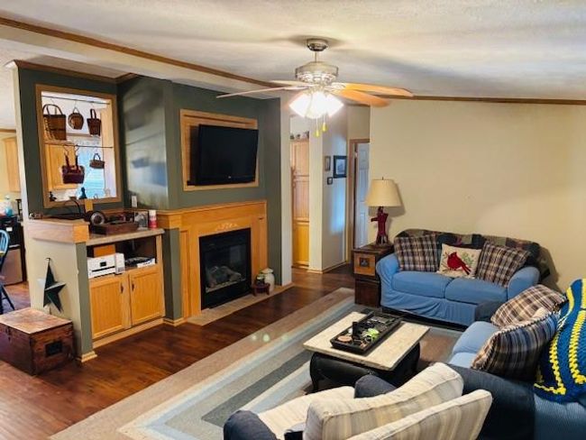 Living room with a fireplace with flush hearth, a ceiling fan, ornamental molding, and dark wood finished floors | Image 6