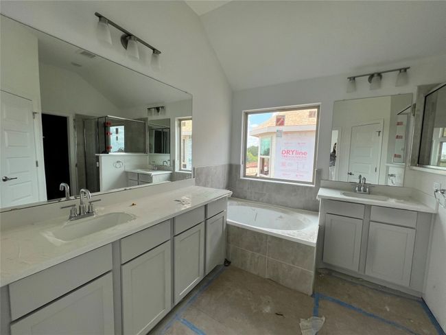 Bathroom featuring lofted ceiling, a bath, two vanities, and a shower stall | Image 8