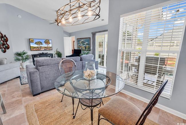 Dining space featuring vaulted ceiling, a chandelier, and light stone finish floors | Image 11