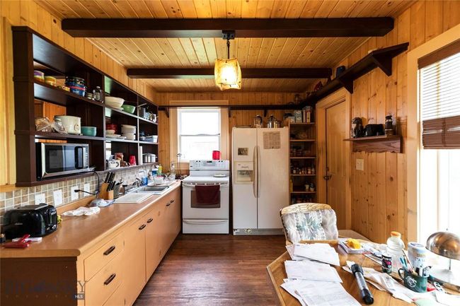 Kitchen featuring beamed ceiling, white appliances, decorative light fixtures, and a wealth of natural light | Image 25