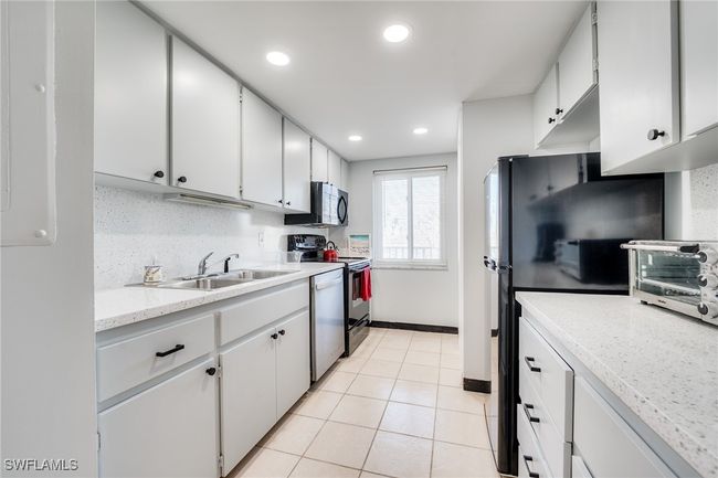 Kitchen with white cabinetry, stainless steel appliances, sink, and backsplash | Image 6