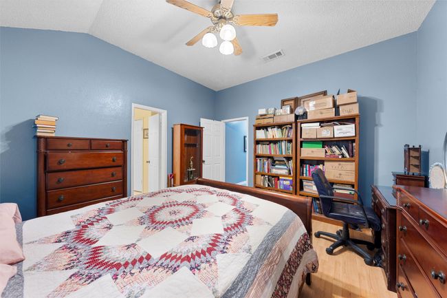 Bedroom with wood finished floors, lofted ceiling, a desk, a textured ceiling, and a ceiling fan | Image 9