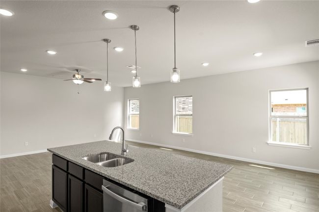 Kitchen featuring open floor plan, stainless steel dishwasher, light wood-style flooring, a ceiling fan, and hanging light fixtures | Image 16