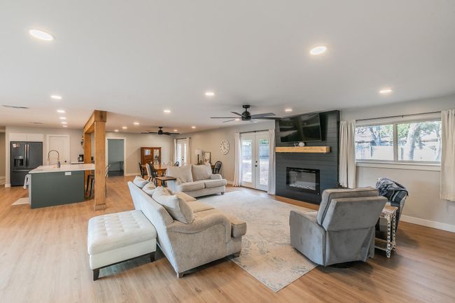 Living room featuring a ceiling fan, recessed lighting, a fireplace, and light wood-type flooring | Image 9