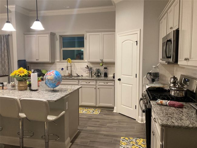 Kitchen featuring ornamental molding, a kitchen bar, stainless steel appliances, and tasteful backsplash | Image 7