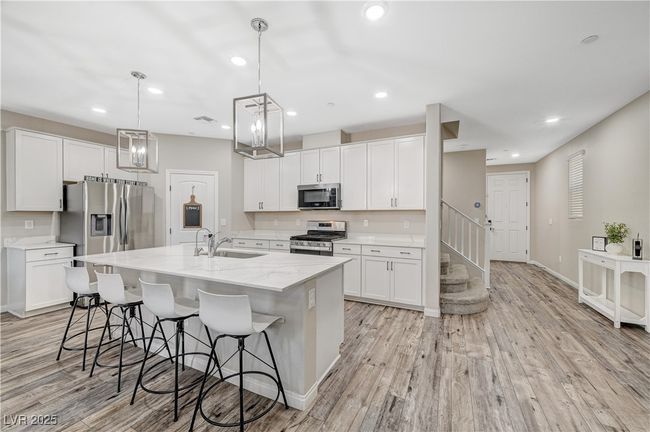 Kitchen with stainless steel appliances, a sink, white cabinetry, an island with sink, and recessed lighting | Image 19