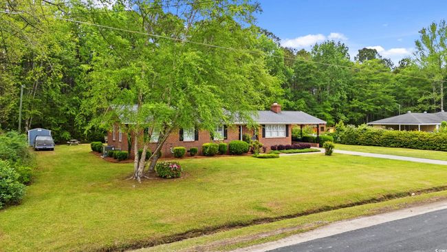 View of front of property featuring brick siding, a chimney, a front lawn, and concrete driveway | Image 21