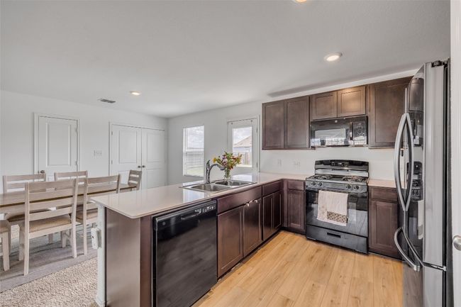Kitchen with black appliances, a peninsula, dark brown cabinets, light countertops, and recessed lighting | Image 16