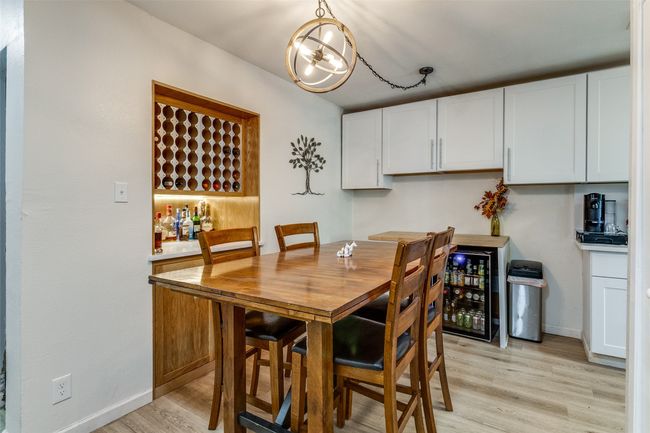 Dining area with beverage cooler, baseboards, light wood-type flooring, and an inviting chandelier | Image 12