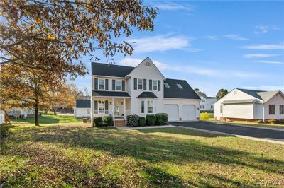 View of front facade featuring a front yard, a porch, and a garage | Image 2