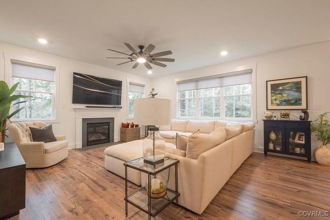 Living room featuring healthy amount of natural light, wood finished floors, a glass covered fireplace, ceiling fan, and recessed lighting | Image 22