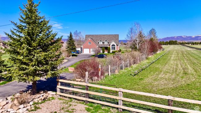 Exterior space featuring a mountain view, a fenced front yard, a rural view, aphalt driveway, and a garage | Image 8