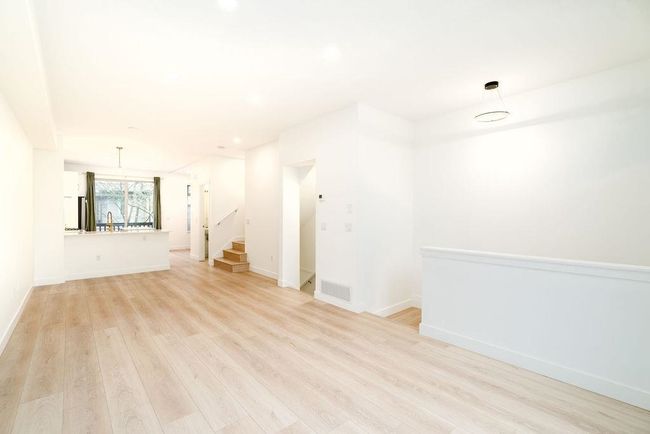 Unfurnished living room with baseboards, light wood-style floors, stairway, and visible vents | Image 13