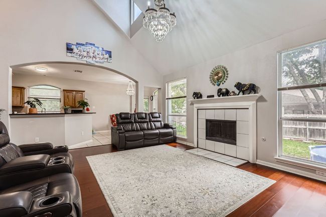 Living area featuring arched walkways, high vaulted ceiling, dark wood finished floors, a tile fireplace, and plenty of natural light | Image 5
