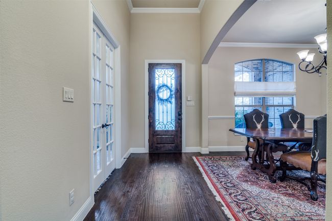 Foyer entrance has solid wood decorative door, raised ceiling with ornamental molding, arched walkways, and luxury handscraped hardwood flooring. The privacy office and dining area flank either side of the entry. | Image 4