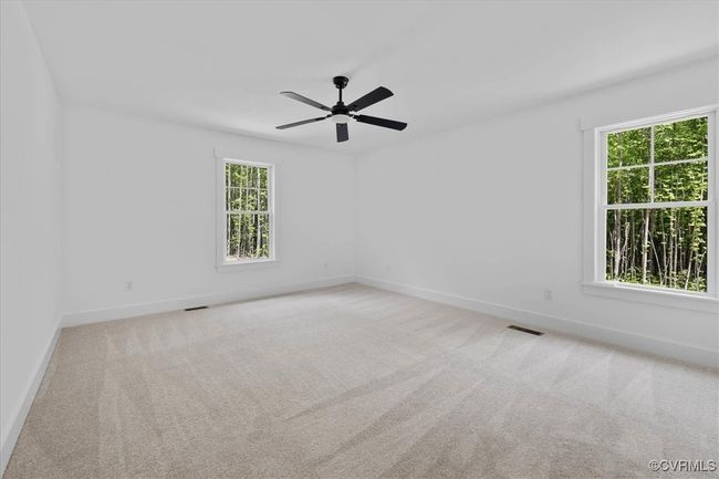 Empty room with carpet flooring, visible vents, baseboards, and a ceiling fan | Image 17