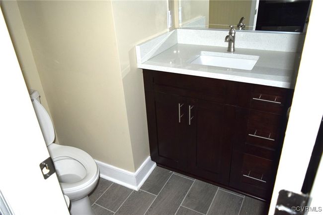 Half bathroom with toilet, vanity, baseboards, and wood finished floors | Image 4