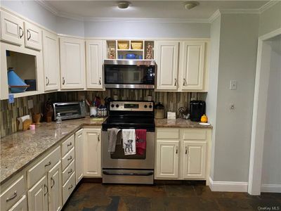 Kitchen featuring light stone countertops, stainless steel appliances, backsplash, and ornamental molding | Image 2