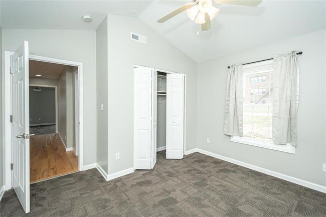 Unfurnished bedroom featuring visible vents, dark carpet, a closet, baseboards, and vaulted ceiling | Image 31