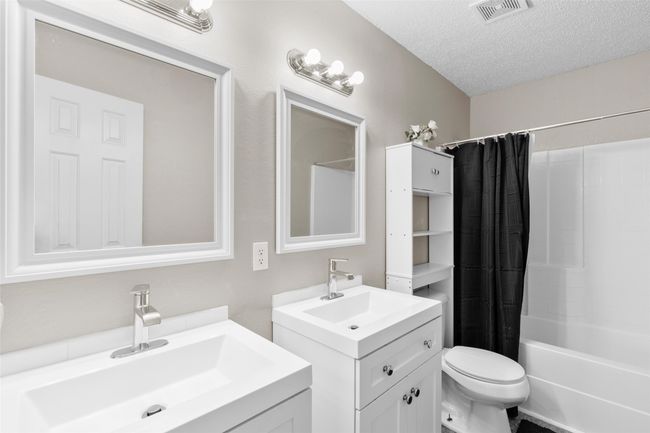 Bathroom with two vanities, shower / tub combo, and a textured ceiling | Image 22