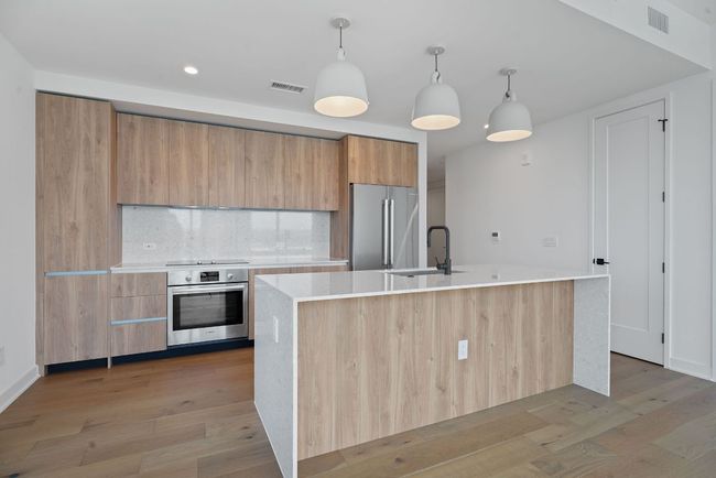 Kitchen with appliances with stainless steel finishes, modern cabinets, light countertops, light wood-style floors, and recessed lighting | Image 10