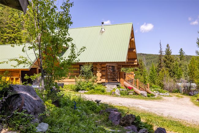View of front facade with log exterior, metal roof, and a view of trees | Image 80