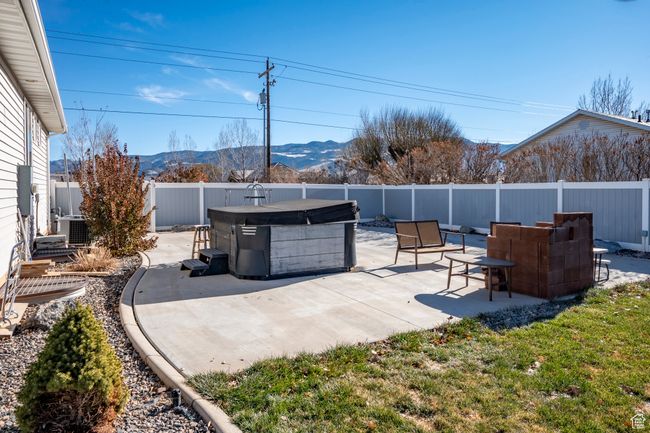 View of patio / terrace with central air condition unit, a mountain view, a fenced backyard, and a hot tub | Image 59