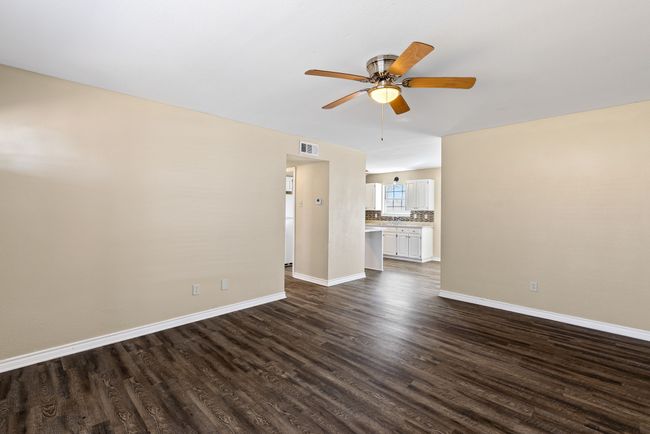 Unfurnished living room with dark wood-style floors, ceiling fan, visible vents, and baseboards | Image 7